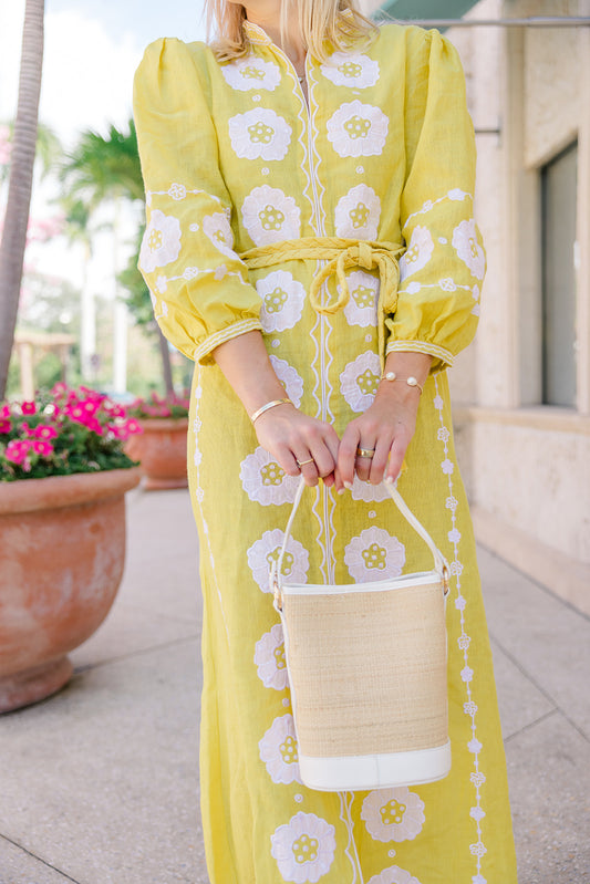 Model wearing a yellow resort sundress carrying the structured Boo rattan tote bag in her hands.