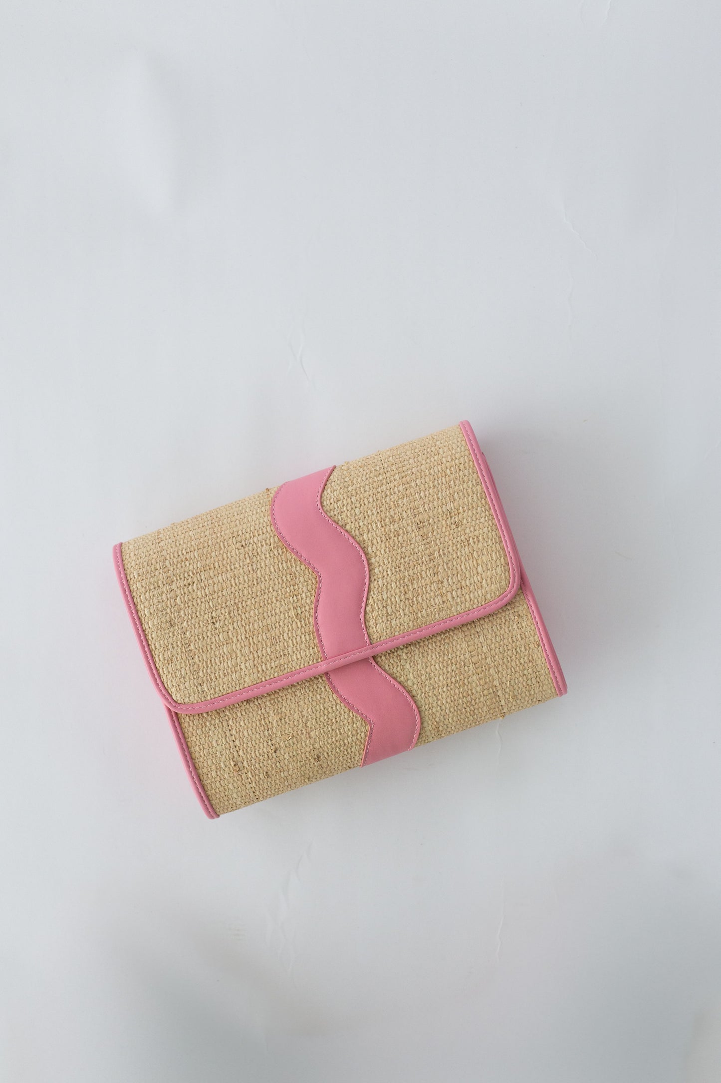 Rattan clutch with pink leather accents on a white background