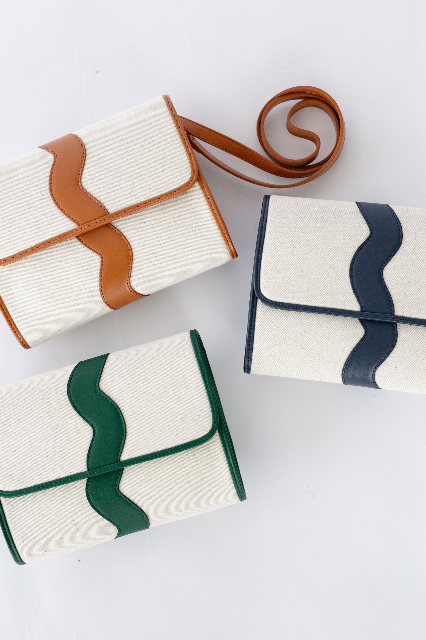 A flat-lay photo of the Allie canvas crossbody clutch in all three colorways.