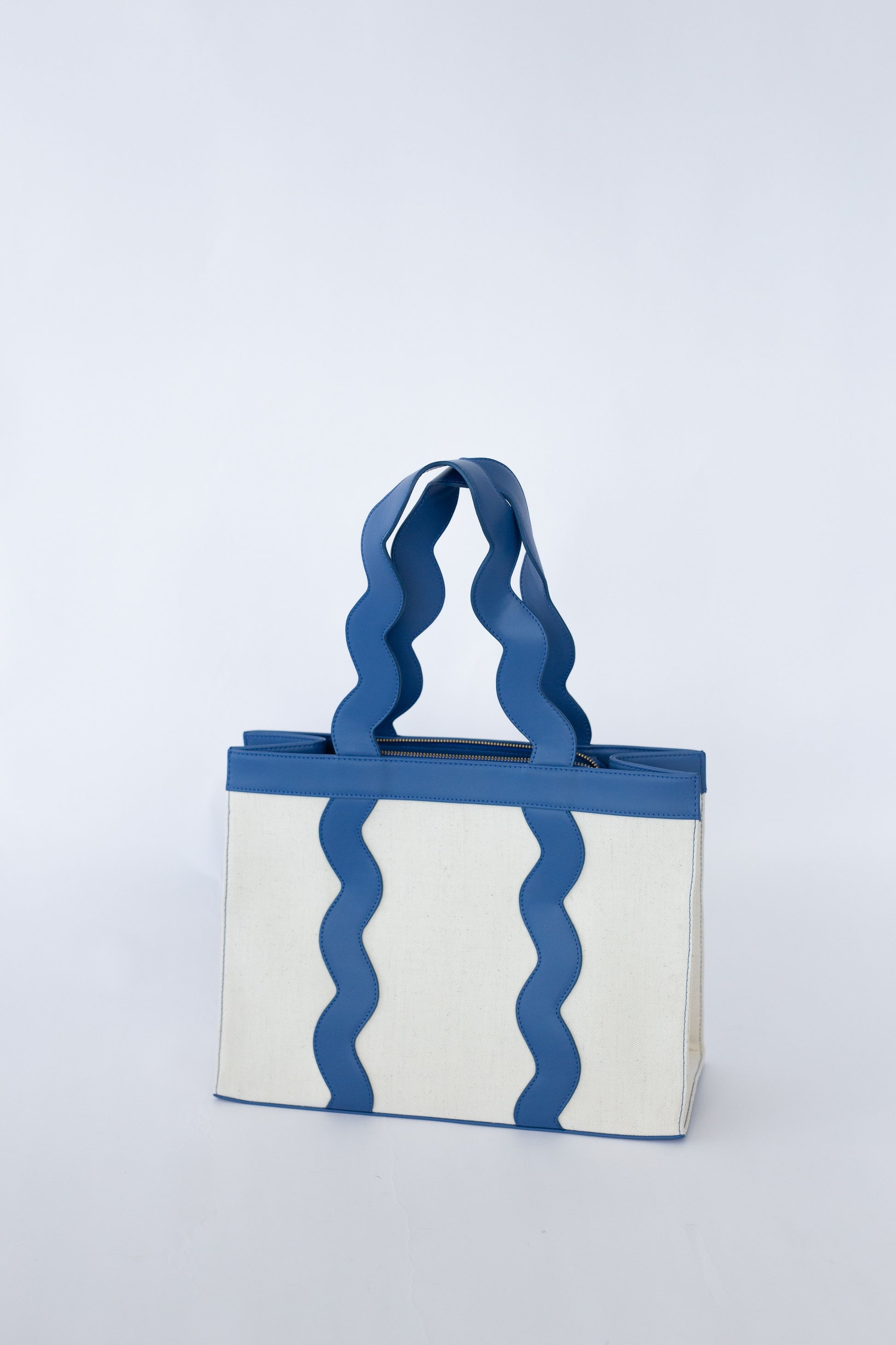 Tote bag with scalloped blue handles and pattern on a white background