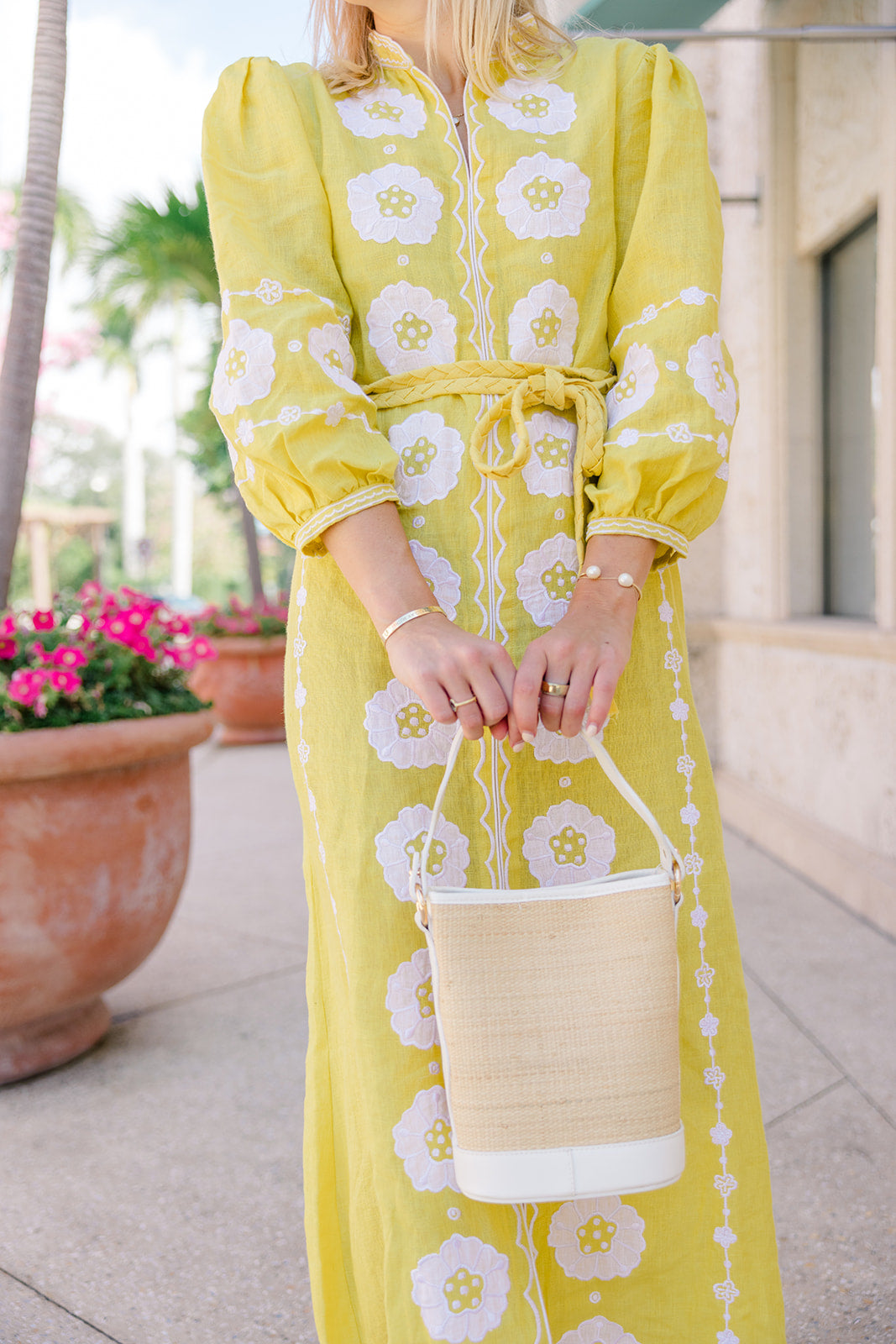 Model wearing a yellow resort sundress carrying the structured Boo rattan tote bag in her hands.
