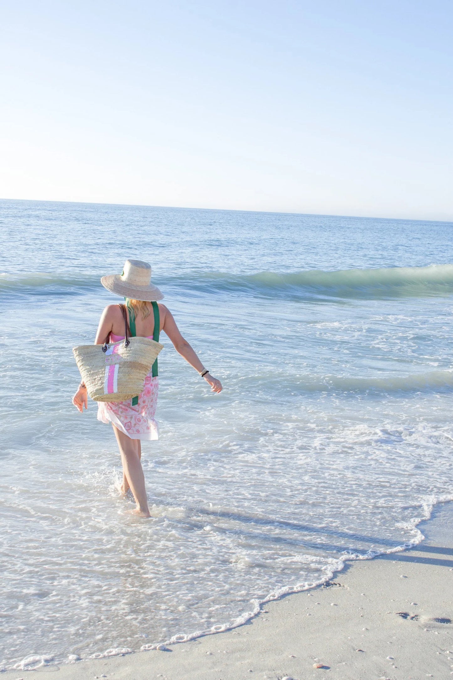 Chic summer styling featuring the Brecky custom monogrammed market bag paired with a classic pink pareo and straw hat.