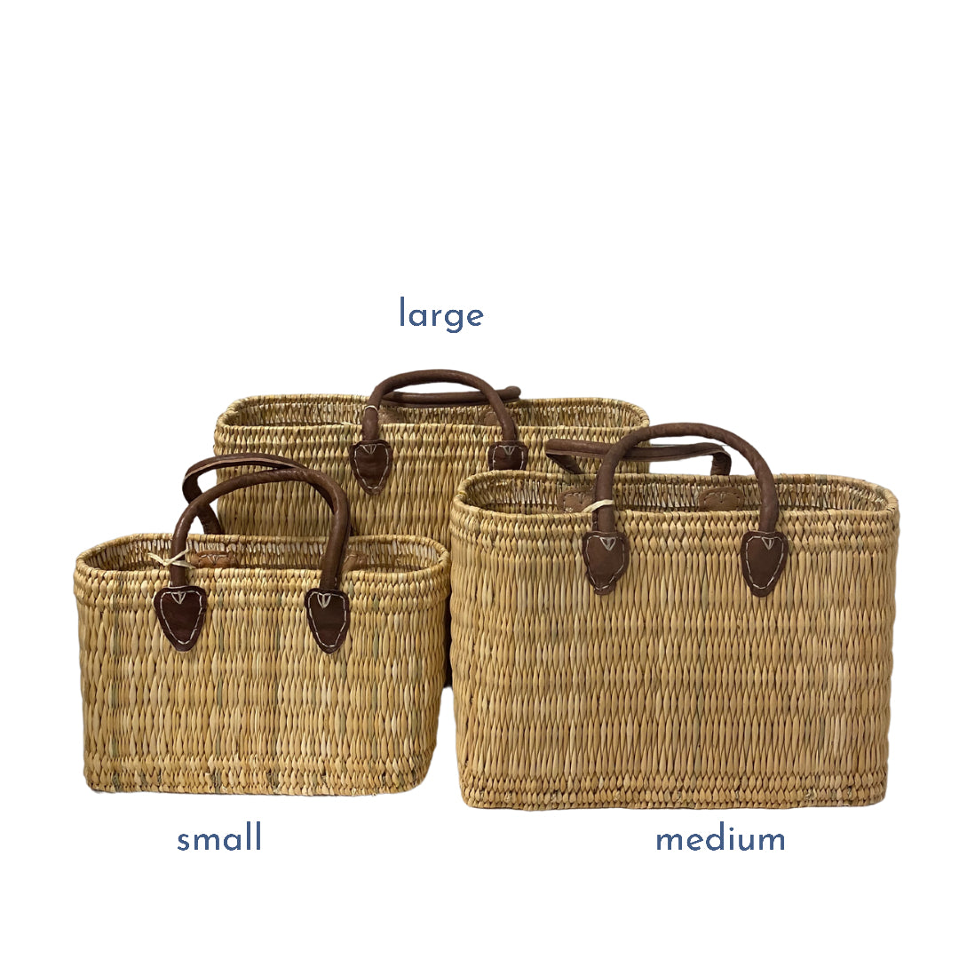 Three woven baskets of different sizes with handles on a white background