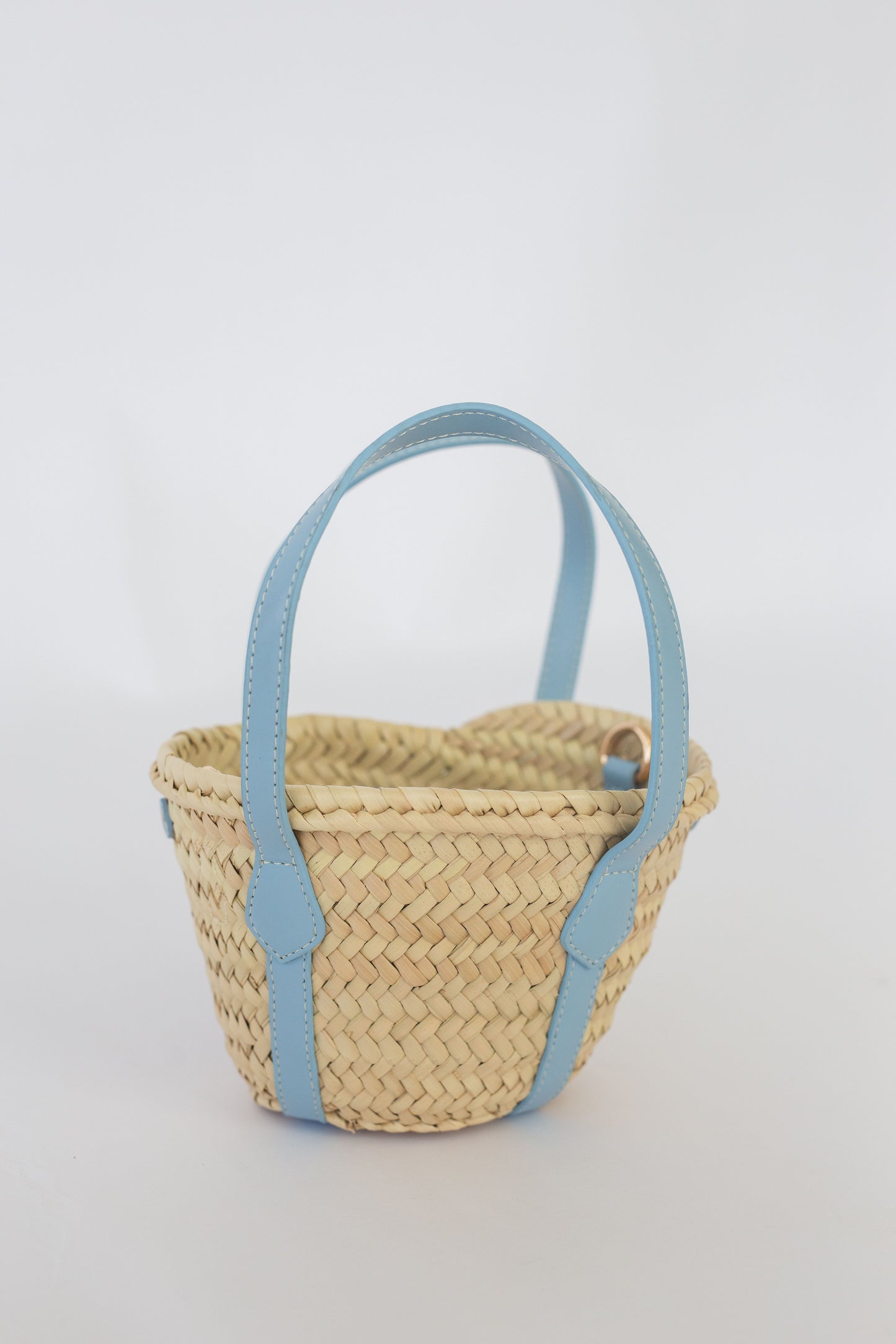 Woven basket with light blue handles on a white background