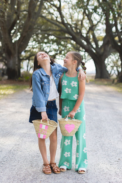 Models carrying a Breck and Grier Painted Heart mini straw tote with summer resort wear outfits
