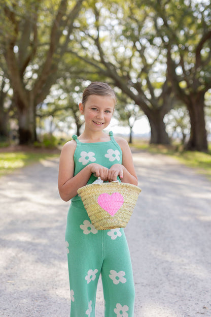 Model carrying a Breck and Grier Painted Heart mini straw tote with summer resort wear outfit