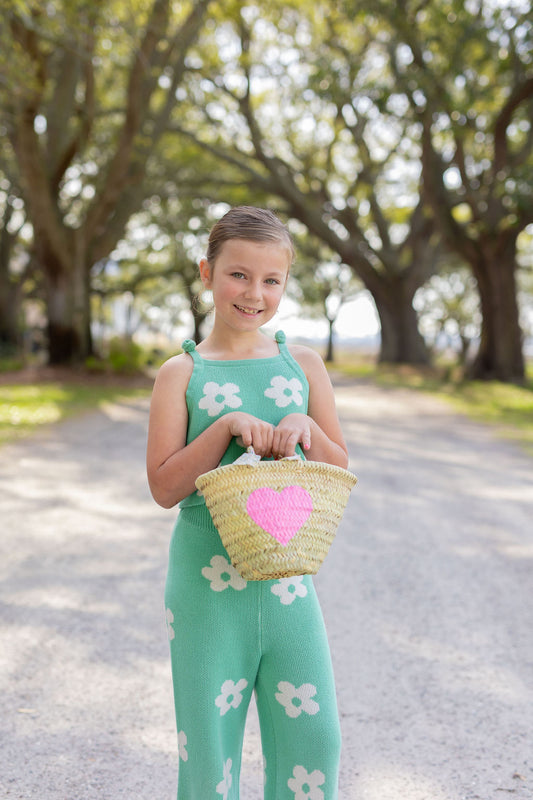 Model carrying a Breck and Grier Painted Heart mini straw tote with summer resort wear outfit