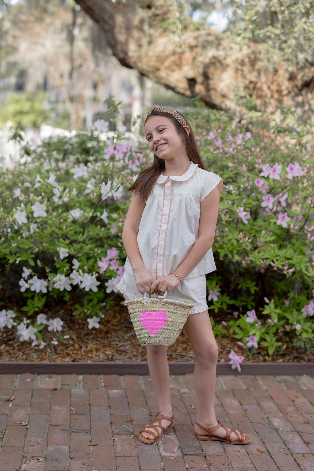 Model carrying a Breck and Grier Painted Heart mini straw tote with summer resort wear outfit