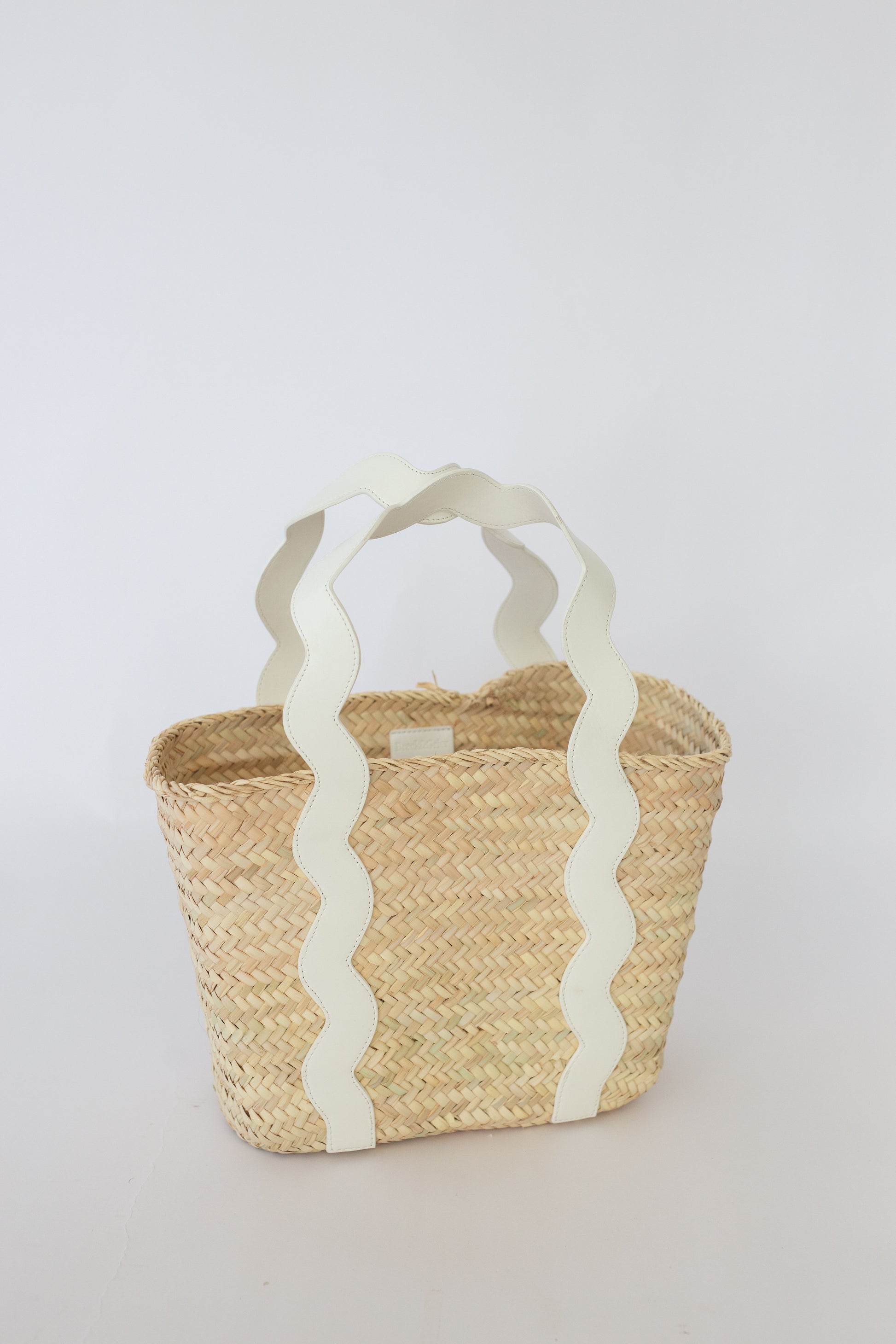 Woven basket with white handle on a light gray background