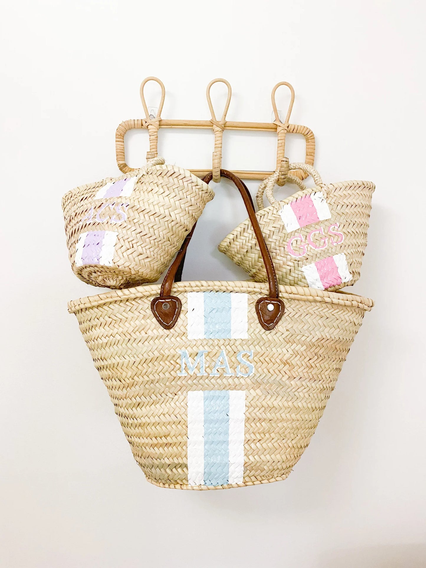 The Mommy and Me matching personalized straw travel bags resting together on a rack, evoking a luxury family vacation vibe.