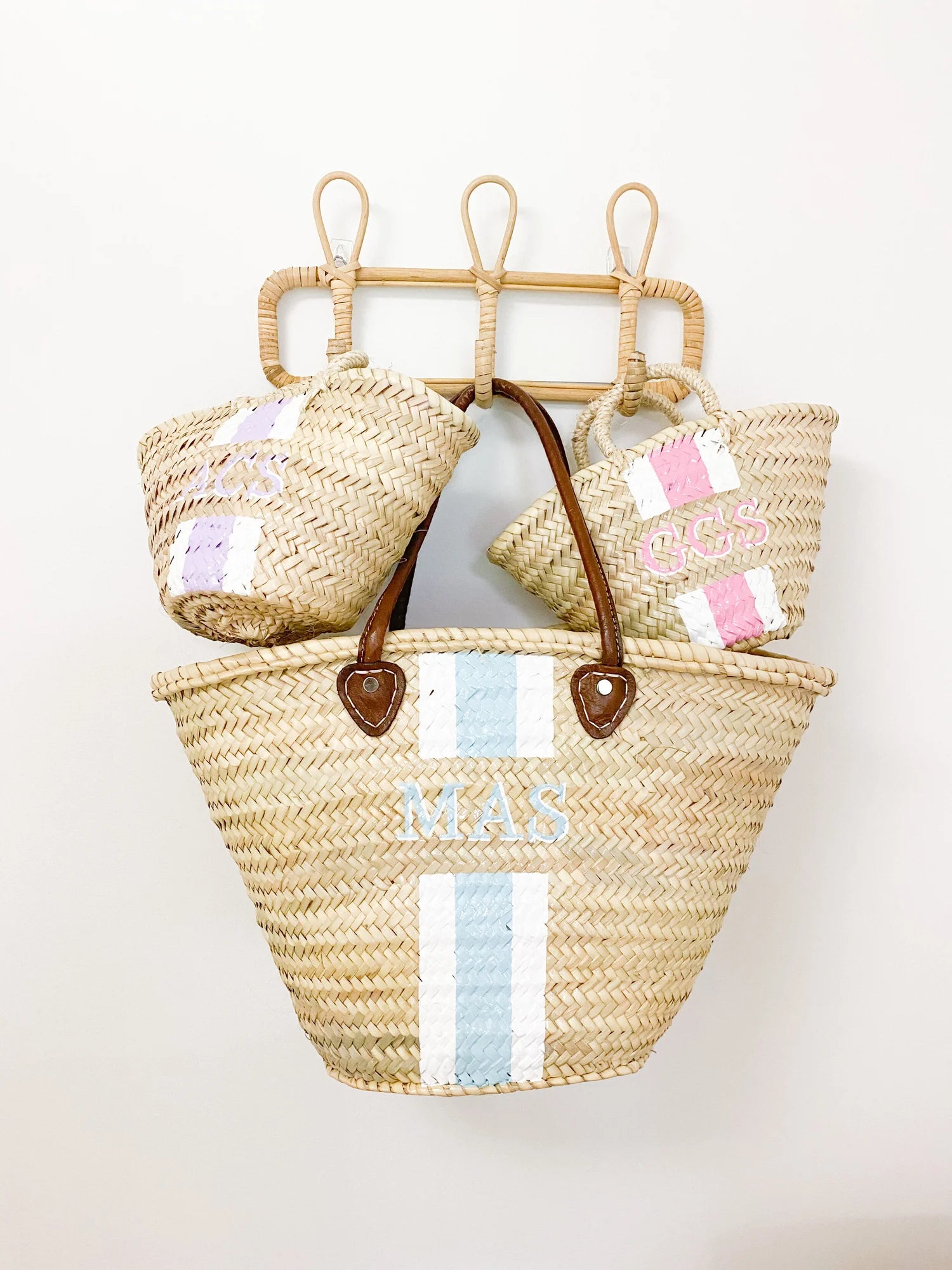 The Mommy and Me matching personalized straw travel bags resting together on a rack, evoking a luxury family vacation vibe.