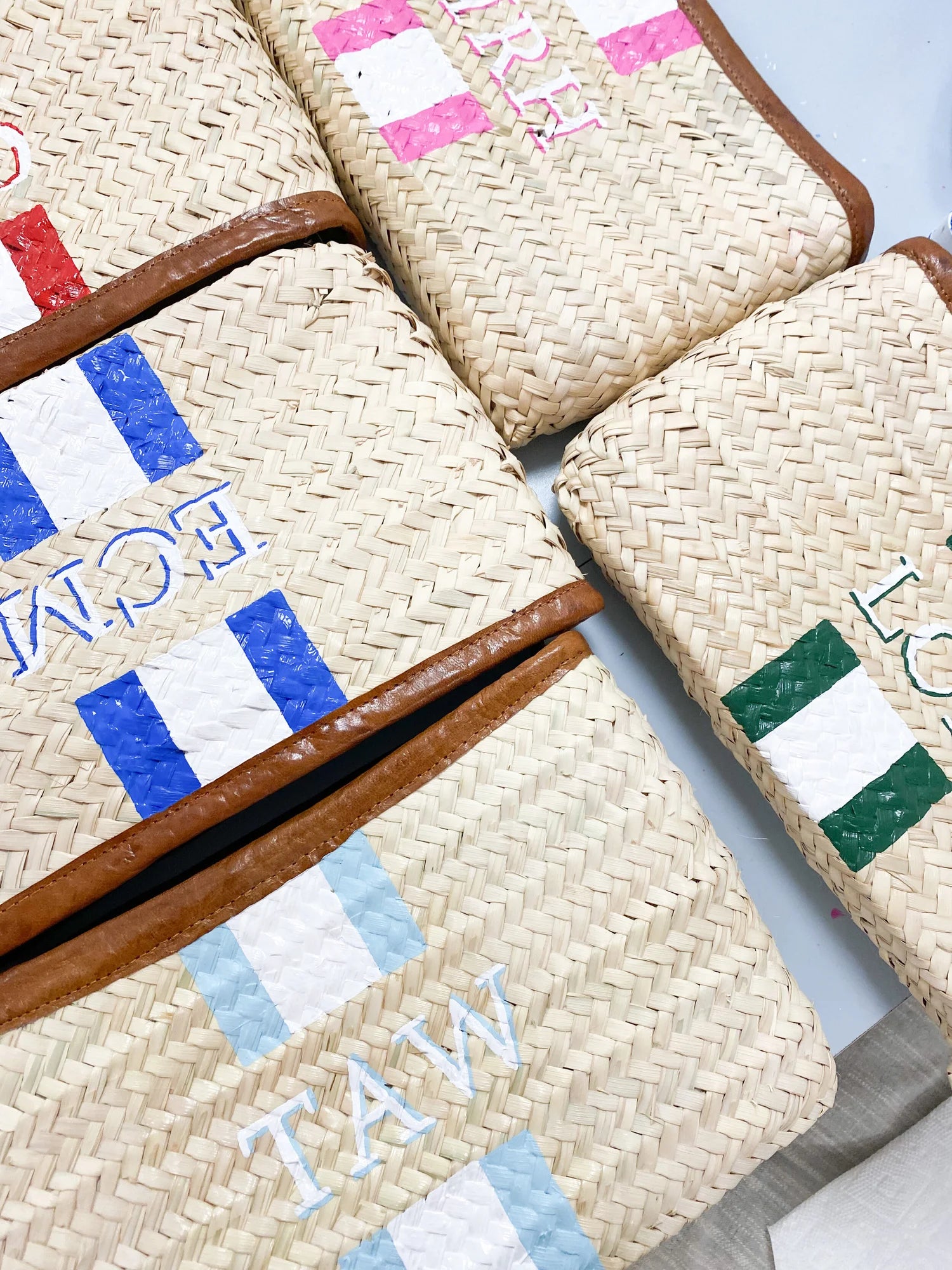 Close up of personalized hand painted initials on the woven Mimi Clutch bags