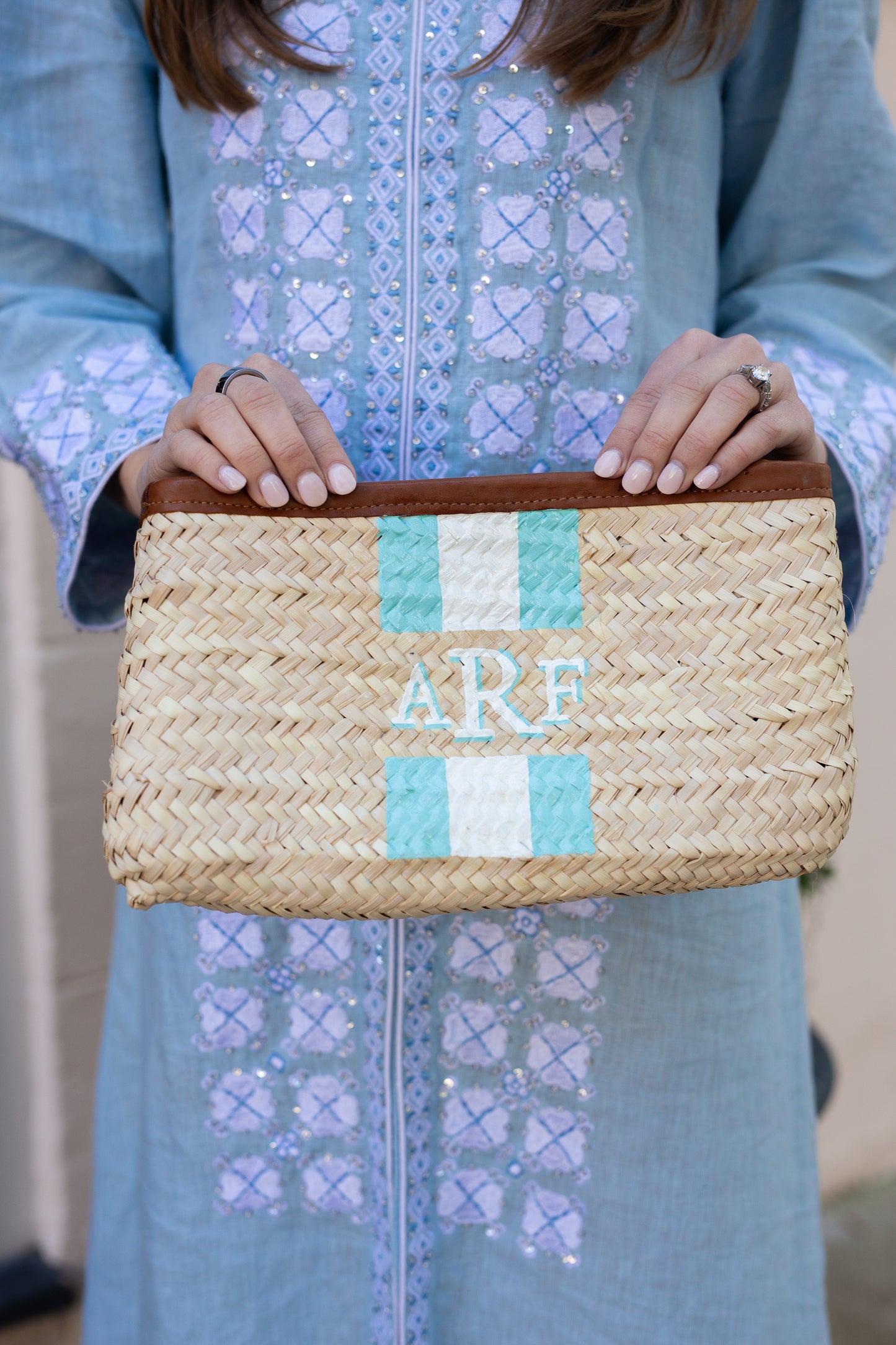 Close up of personalized hand painted initials on the woven Mimi Clutch bag