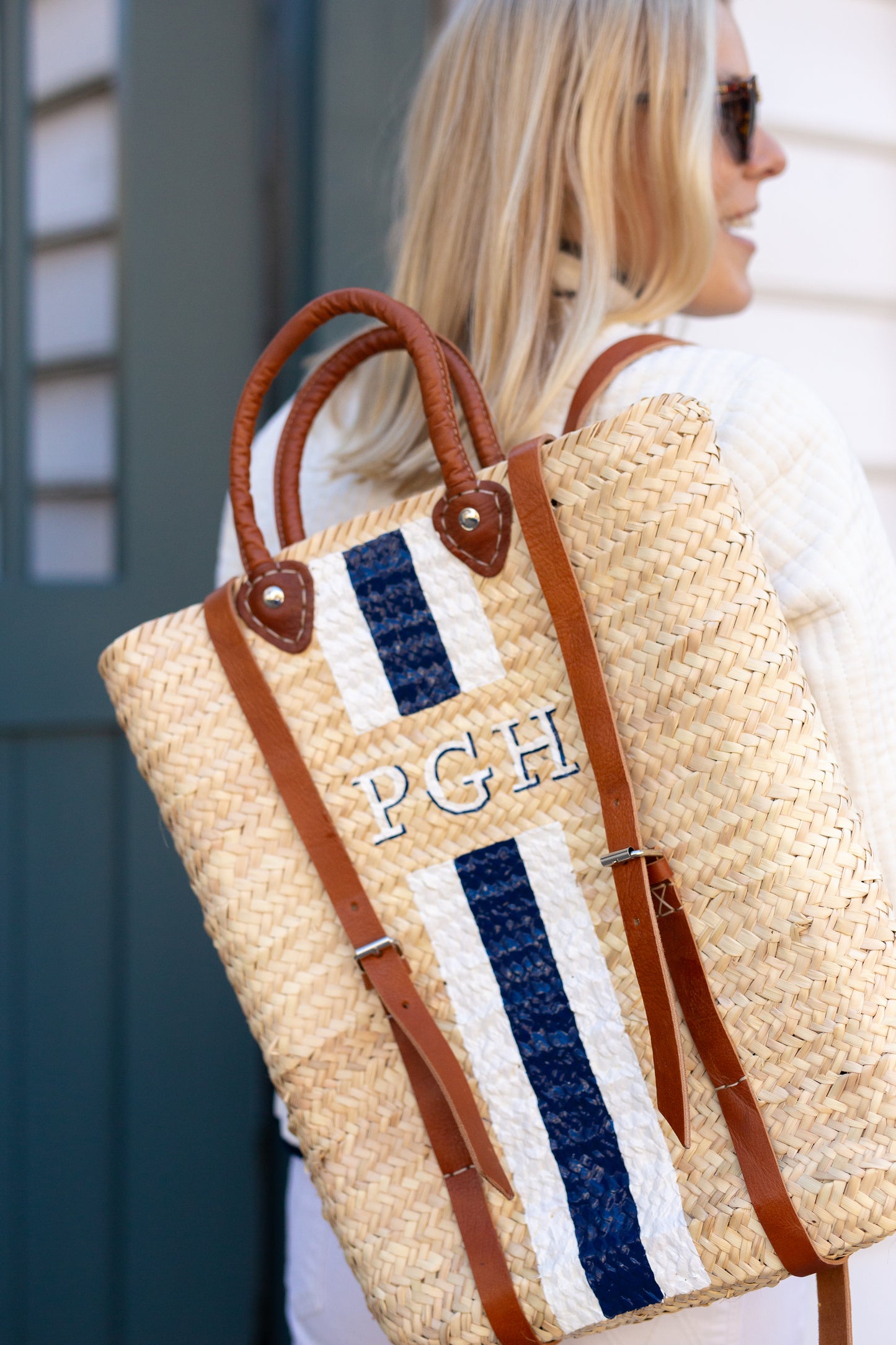 Front view of the custom monogrammed Phebe straw vacation backpack on a model.