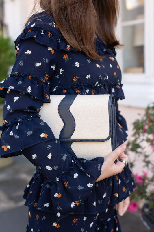 Model wearing a floral fall dress holding the Allie canvas evening clutch purse in her hand.