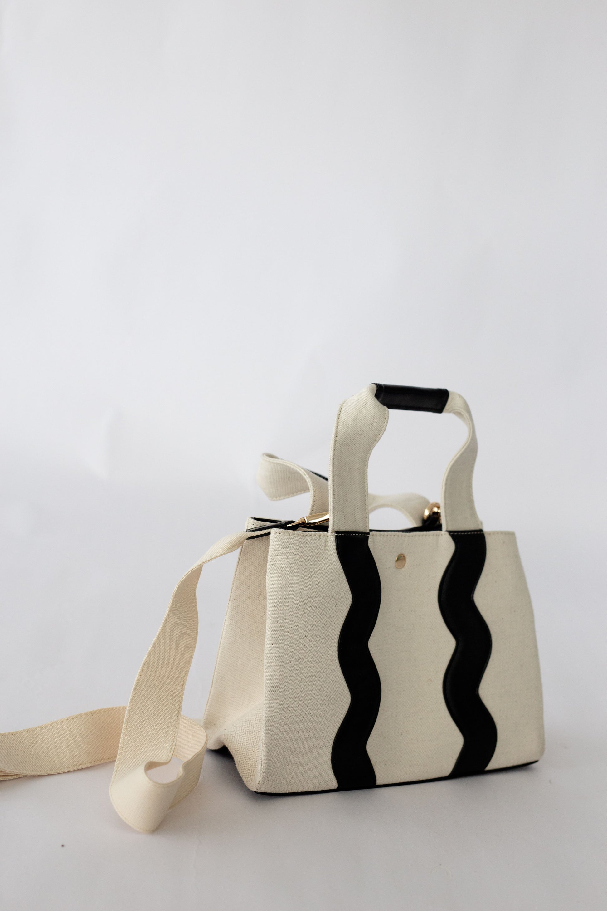 White handbag with black scallop pattern on a white background