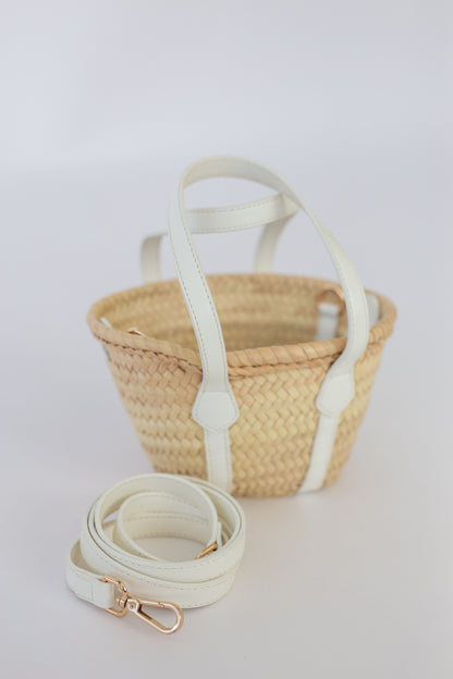Woven basket with a white strap on a light gray background