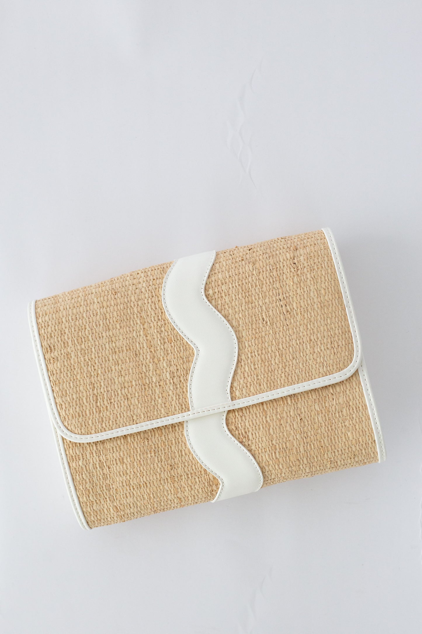 Rattan clutch bag with white strap on a light gray background