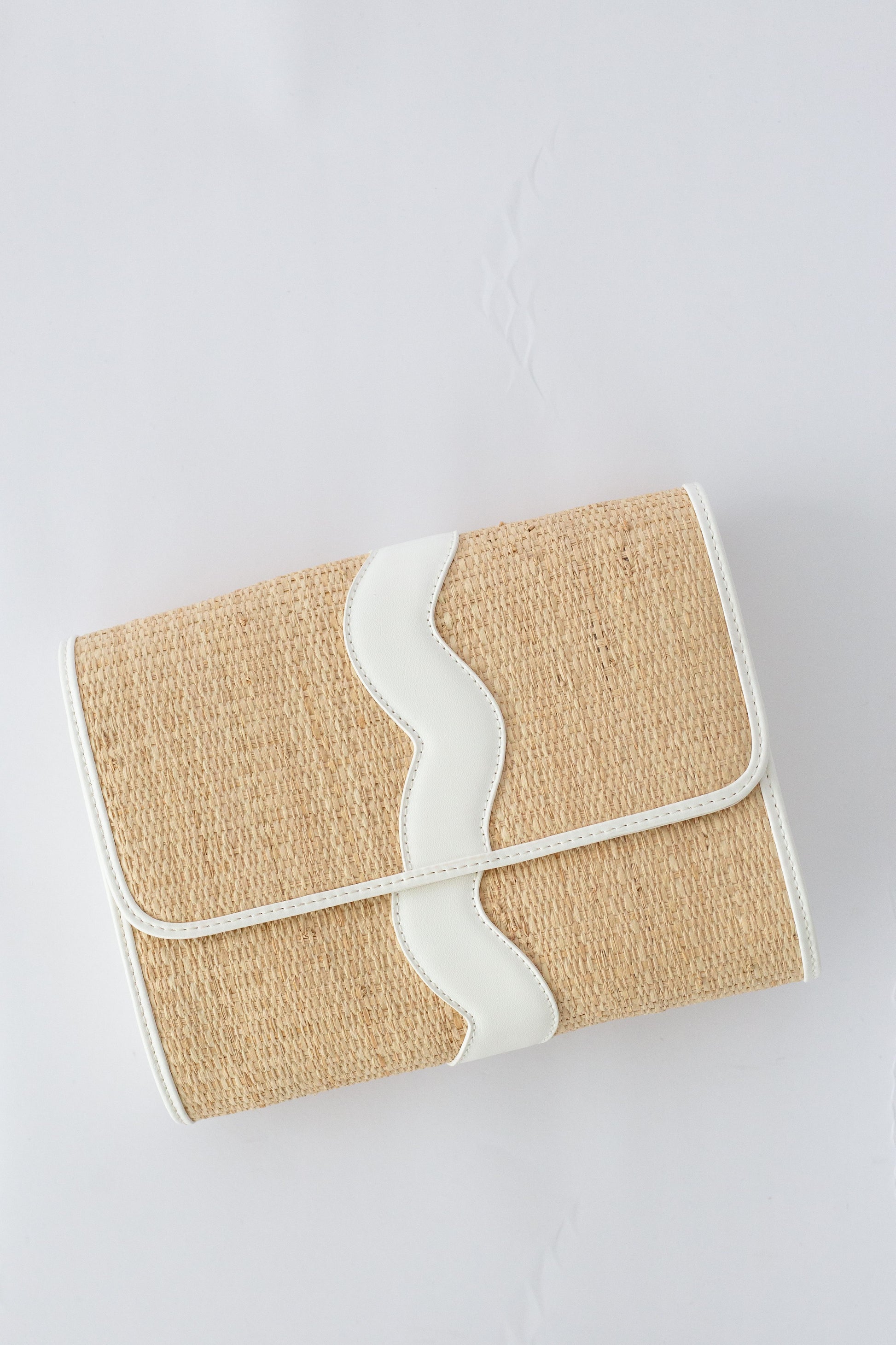 Rattan clutch bag with white strap on a light gray background