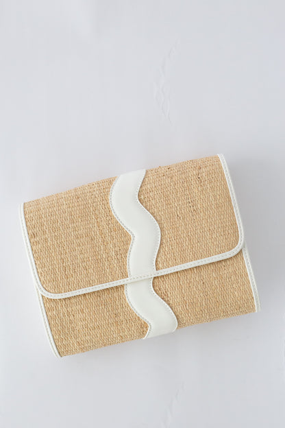 Rattan clutch bag with white strap on a light gray background