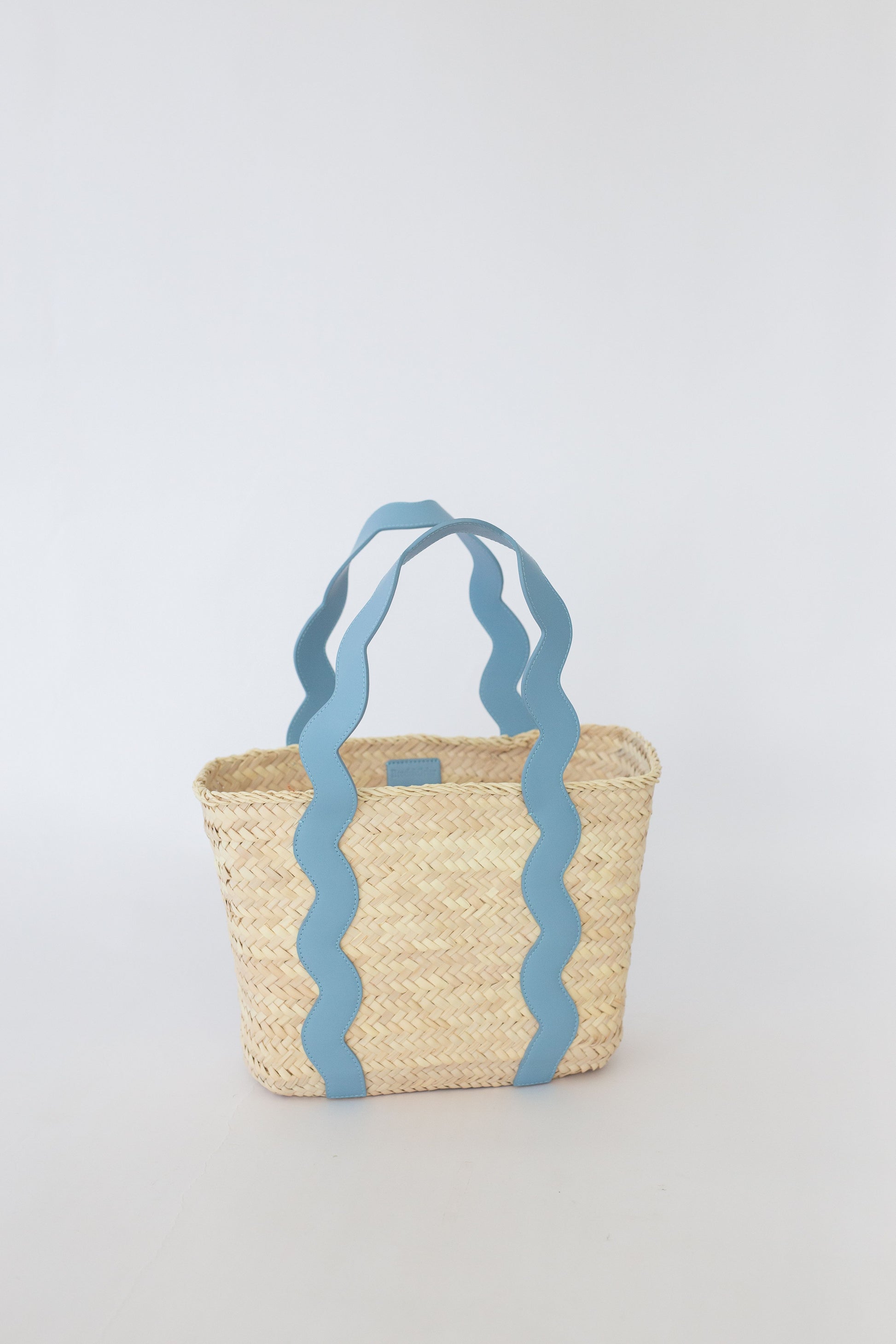 Woven basket with blue wavy handles on a light gray background