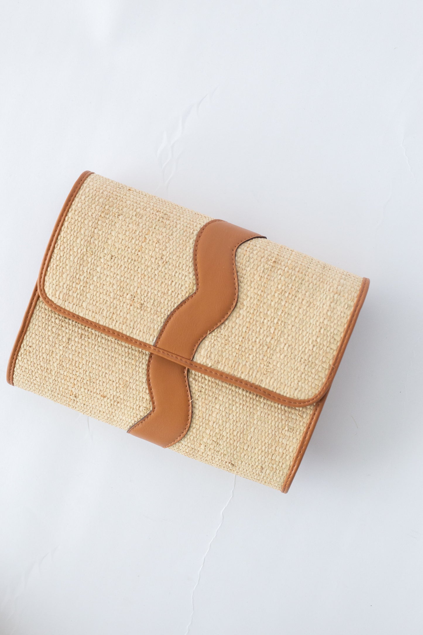 Rattan woven clutch with brown leather accents on a white background