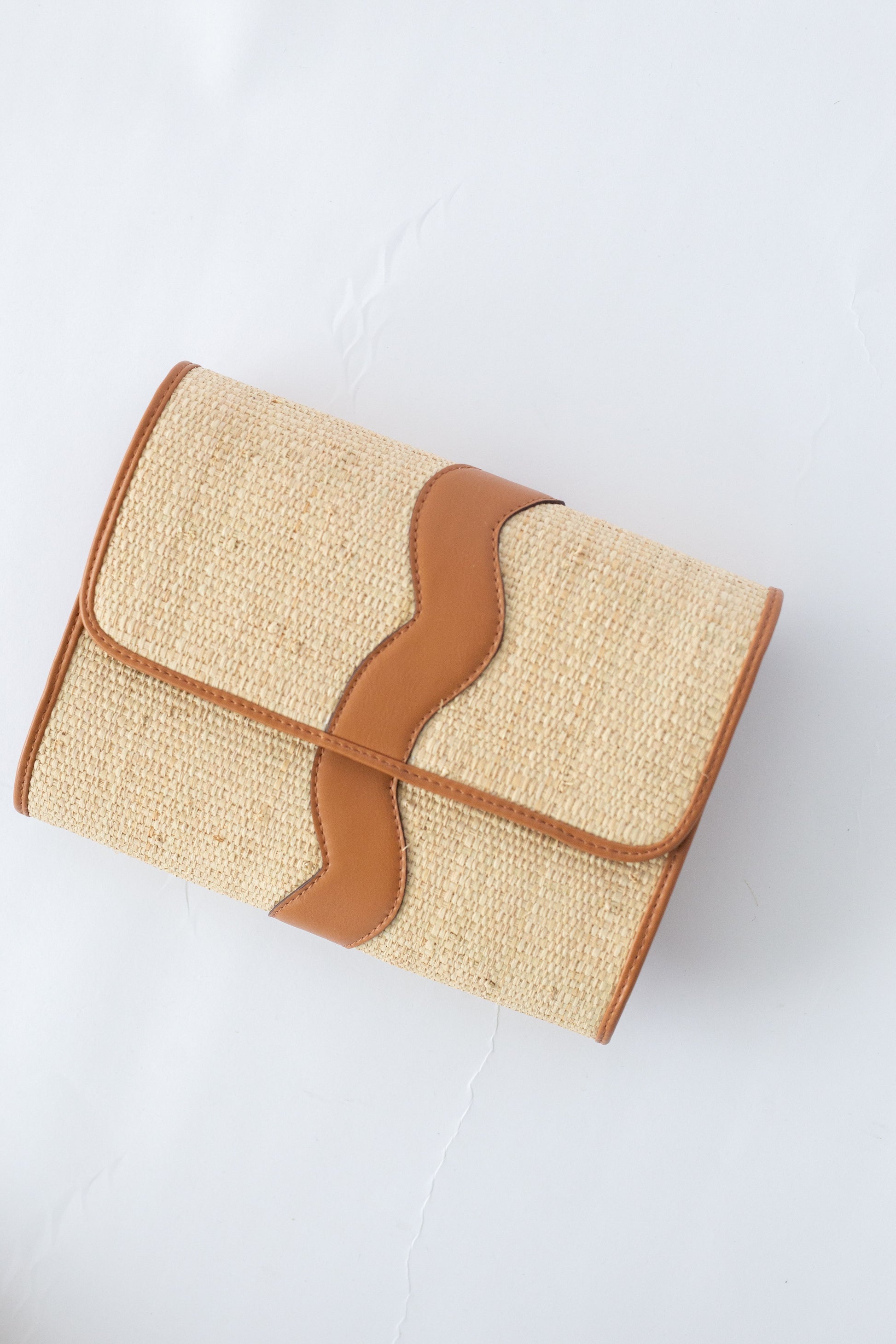 Rattan woven clutch with brown leather accents on a white background