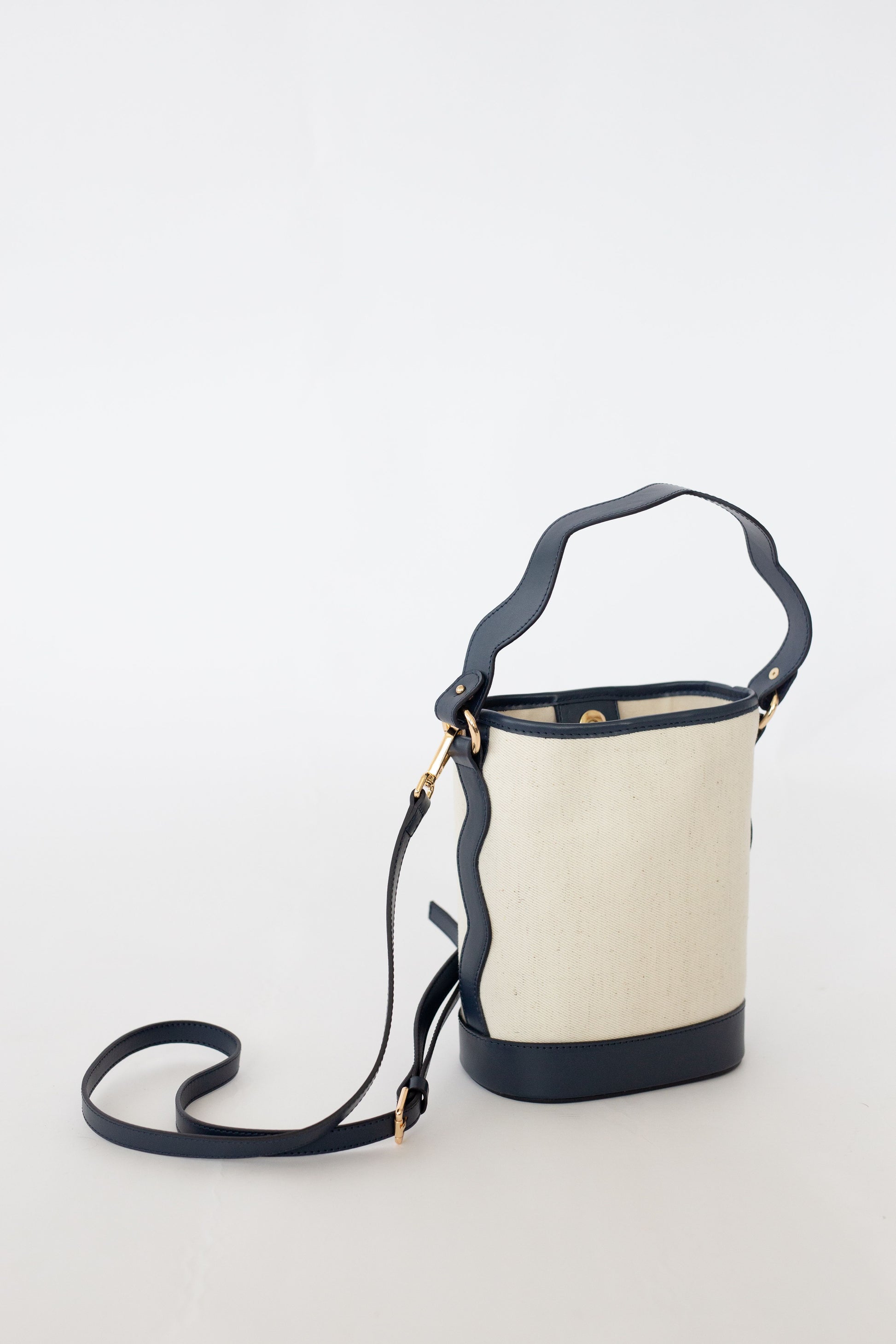 Canvas bucket bag with navy leather accents on a white background