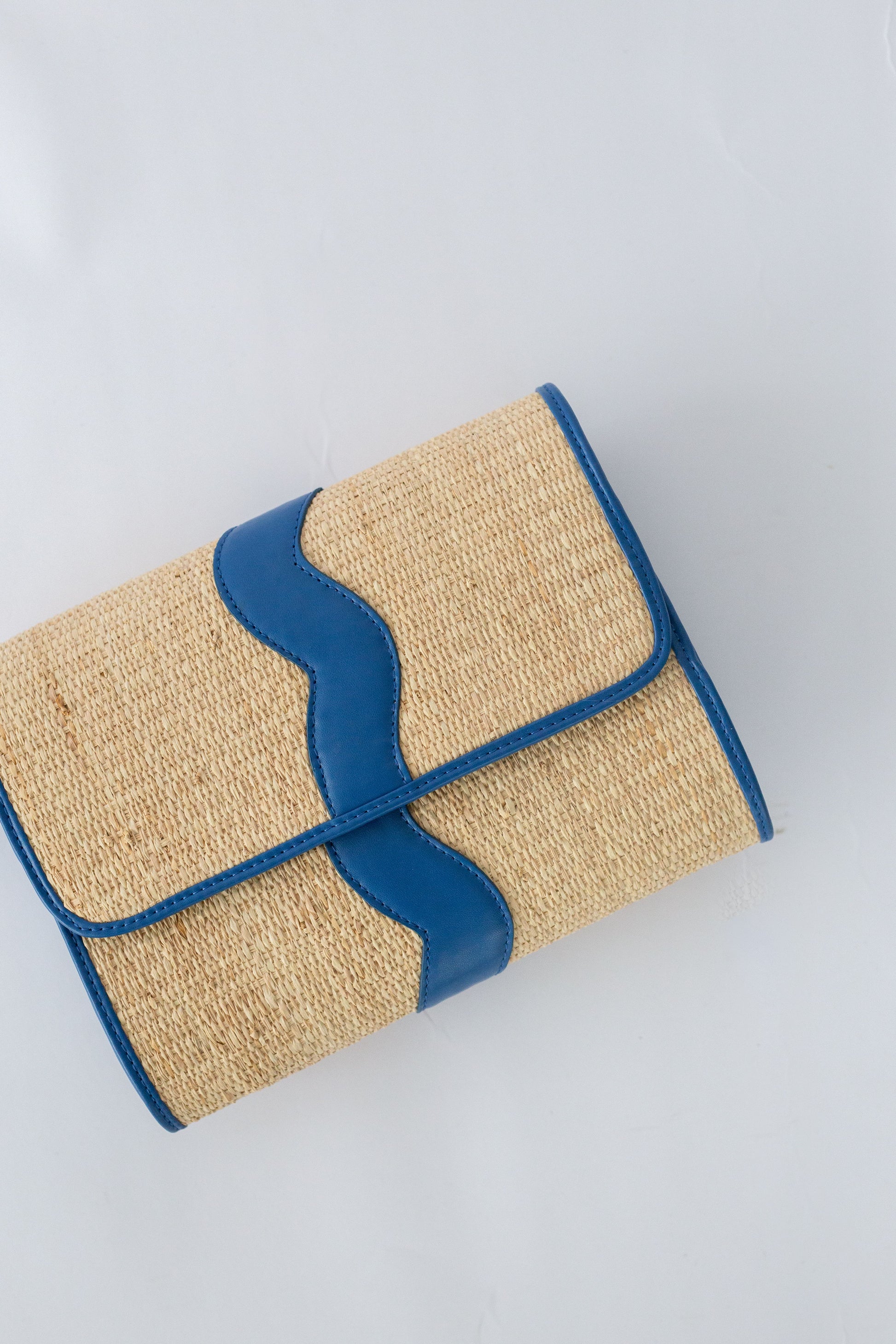 Rattan clutch with navy blue trim on a light gray background