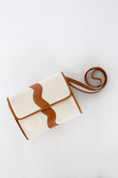 White clutch with brown accents and a matching strap on a white background