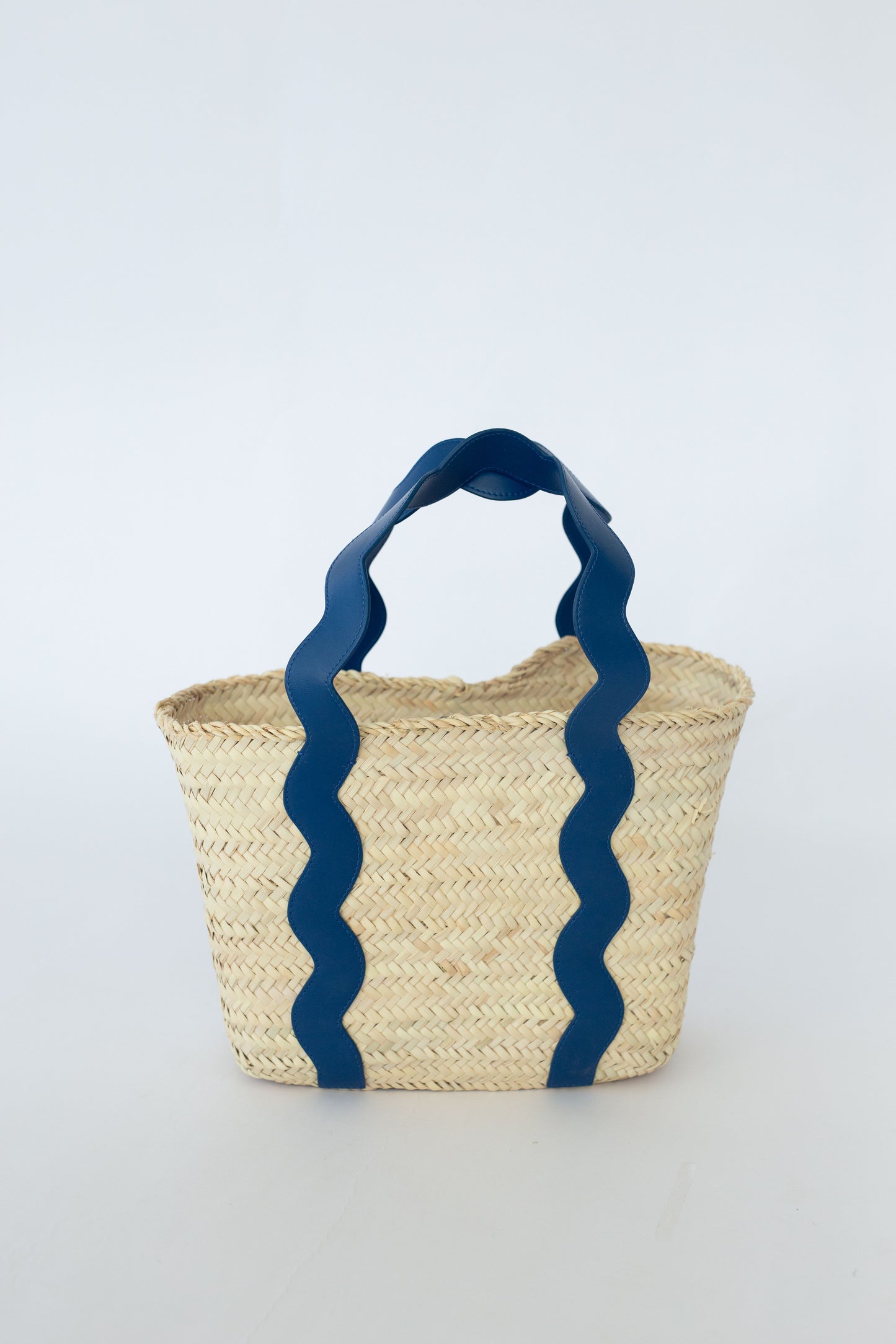 Woven basket with blue handles on a light gray background