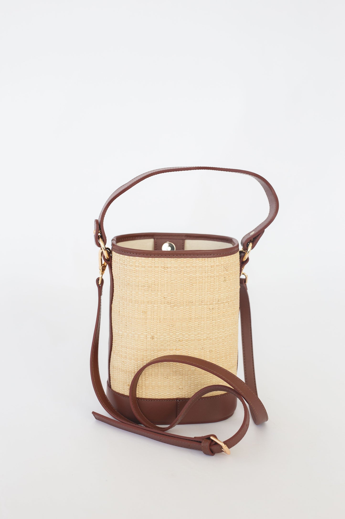 Handbag with straw-like texture and brown leather accents on a white background