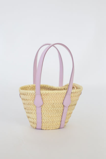 Woven basket with lilac handles on a light gray background
