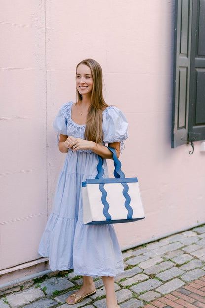 Full view of the structured Grier tote bag showcasing the symmetrical blue scalloped leather handles and trim.